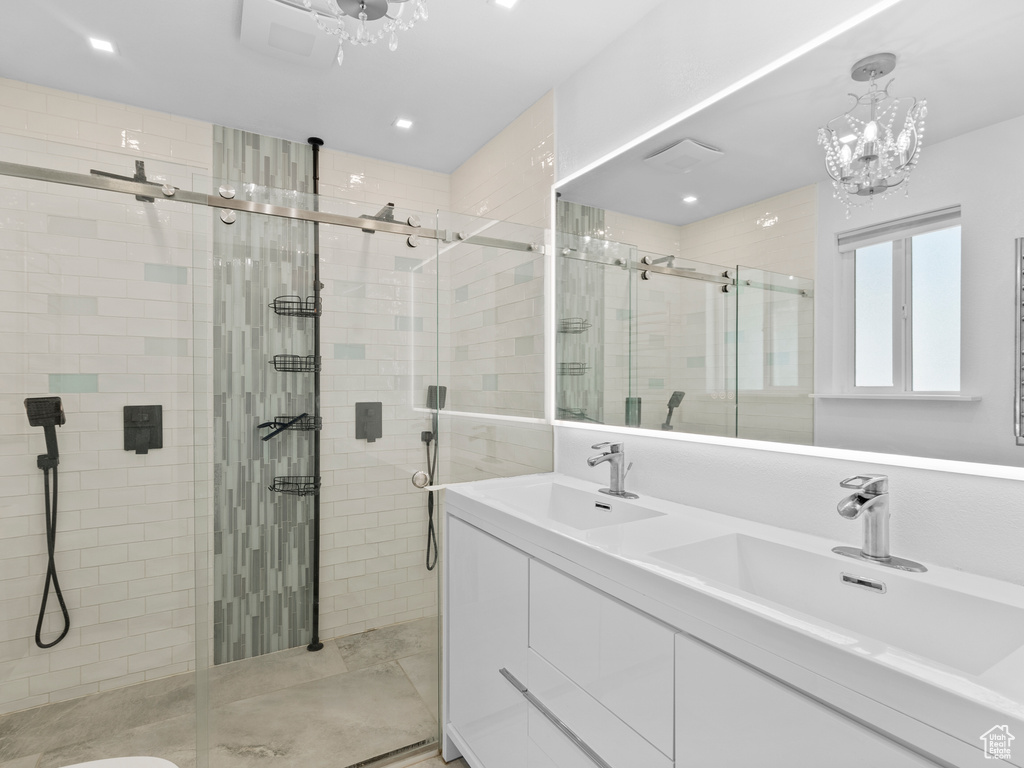 Full bathroom featuring a shower stall, double vanity, a chandelier, and recessed lighting