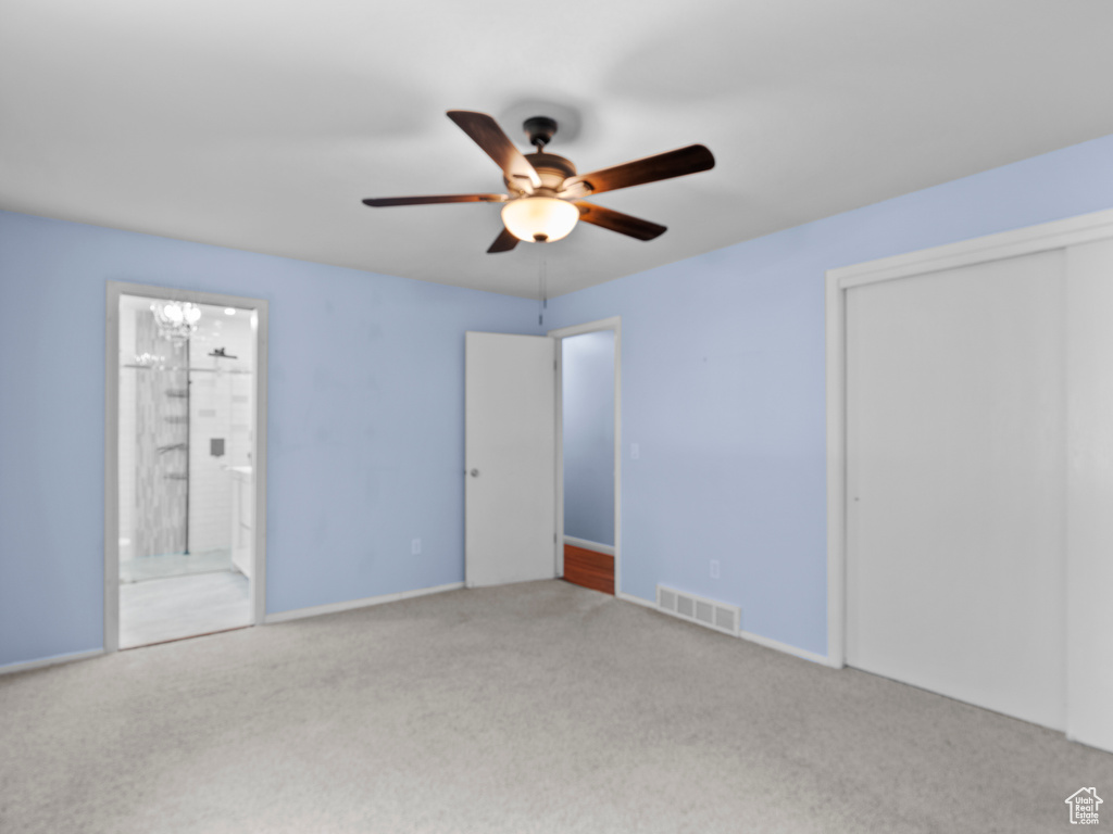 Unfurnished bedroom featuring carpet flooring, a closet, ensuite bath, a chandelier, and a ceiling fan