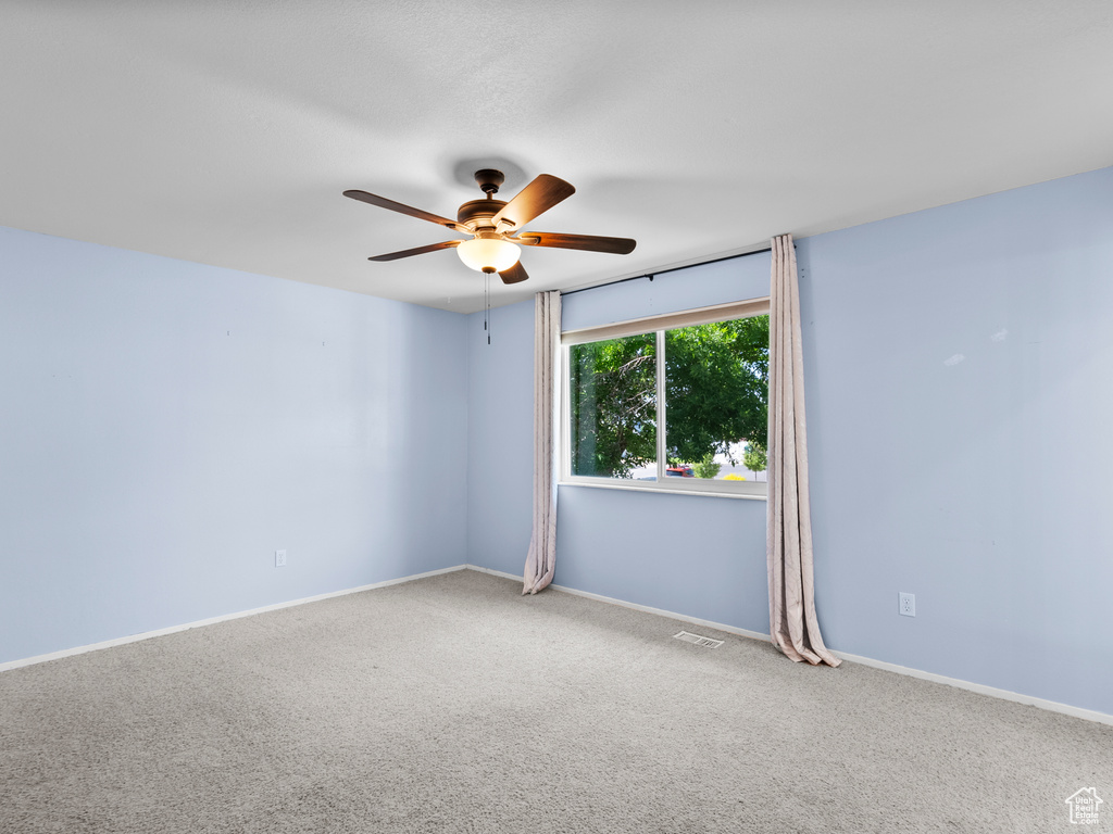 Empty room featuring ceiling fan, carpet floors, and baseboards