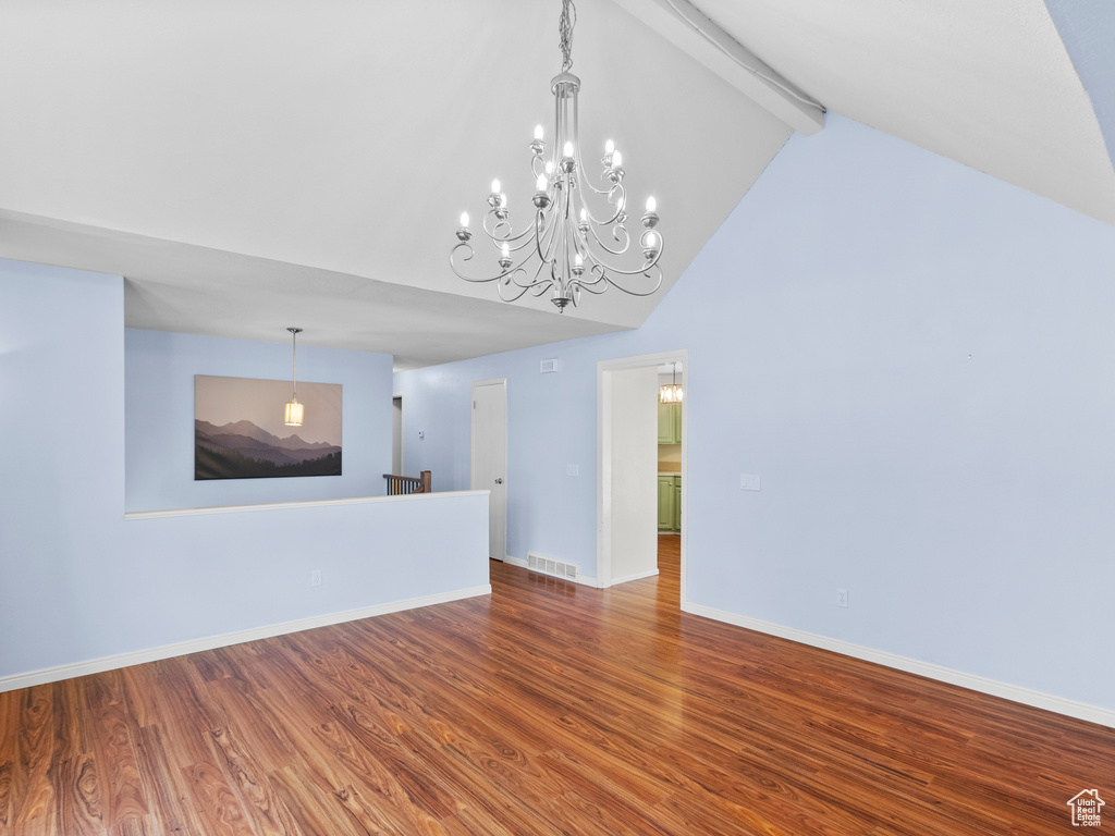 Unfurnished living room featuring beamed ceiling, high vaulted ceiling, wood finished floors, and baseboards
