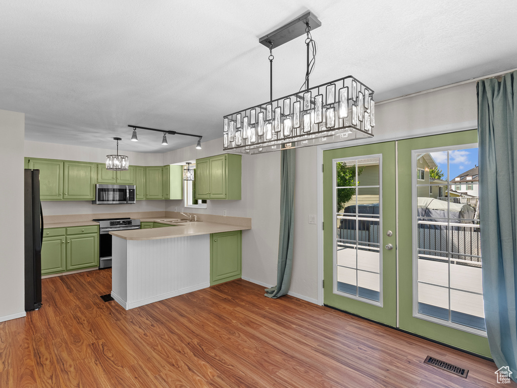 Kitchen with green cabinets, range, stainless steel microwave, and freestanding refrigerator