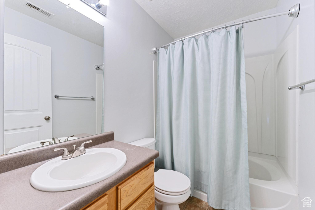 Full bathroom with toilet, vanity, shower / tub combo with curtain, and tile patterned floors