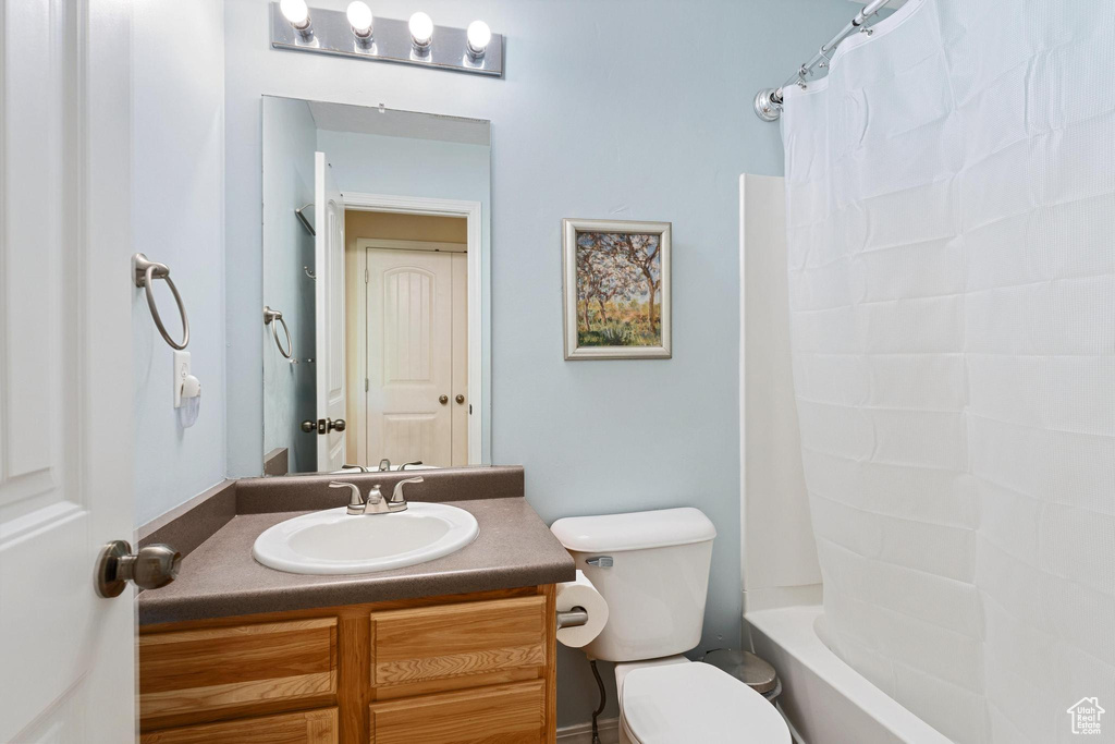Bathroom with vanity, toilet, and shower / bath combo with shower curtain