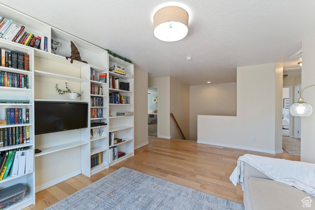 Sitting room with an upstairs landing, wood finished floors, baseboards, and a textured ceiling
