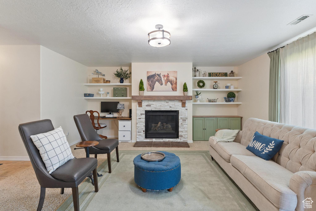 Living room featuring a fireplace, light colored carpet, baseboards, built in features, and a textured ceiling