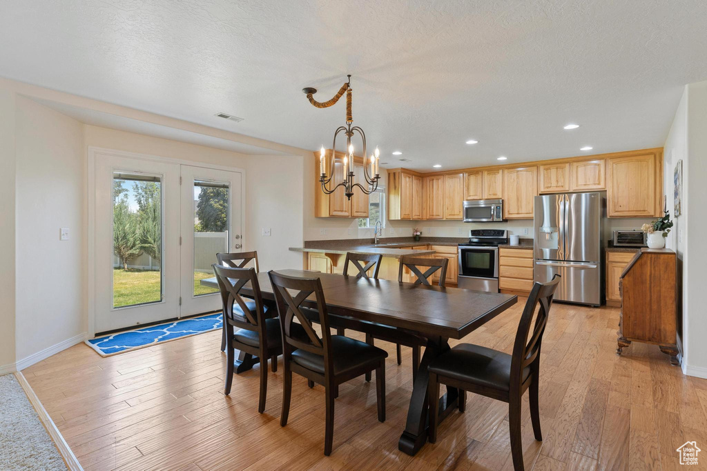 Dining area featuring light wood finished floors, recessed lighting, a chandelier, and baseboards