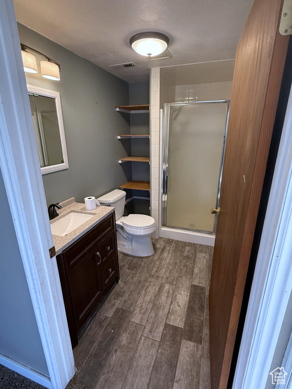 Full bathroom with wood finished floors, vanity, a shower stall, and a textured ceiling