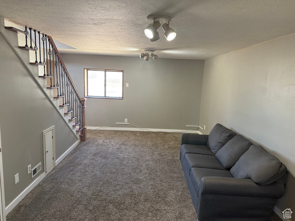 Living area featuring stairway, a textured ceiling, carpet flooring, and a chandelier