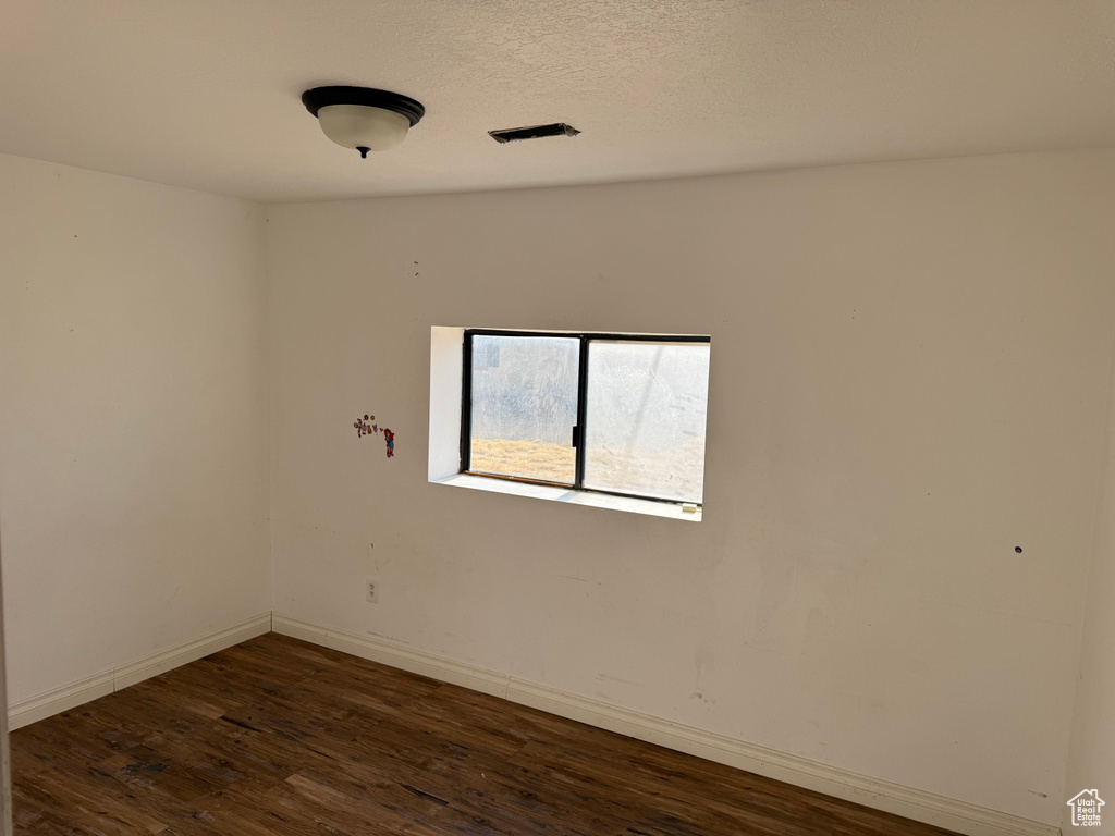 Empty room with dark wood-style flooring and baseboards