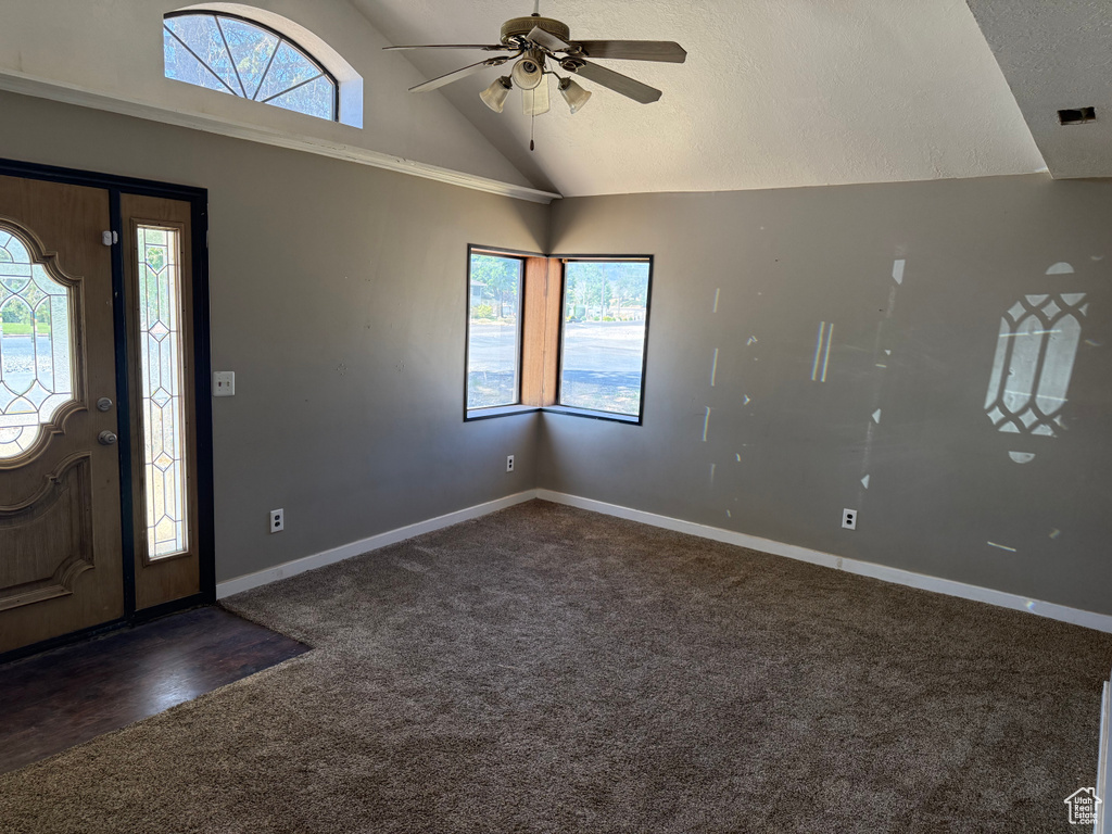Entryway featuring dark colored carpet, ceiling fan, plenty of natural light, and high vaulted ceiling