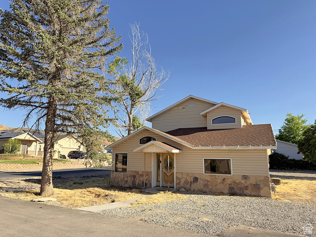 View of front of home with a shingled roof and stone siding