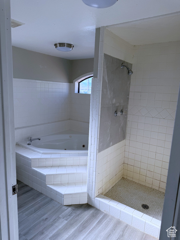 Full bath with wood finished floors, a bath, and tiled shower
