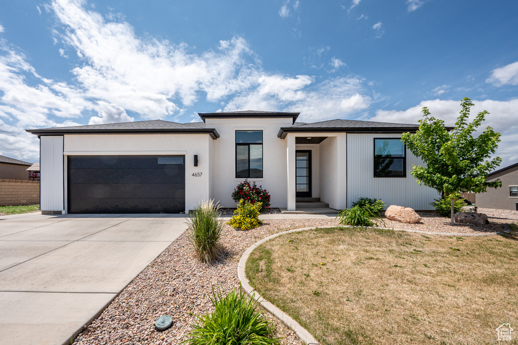 Prairie-style home with concrete driveway, an attached garage, and a front yard