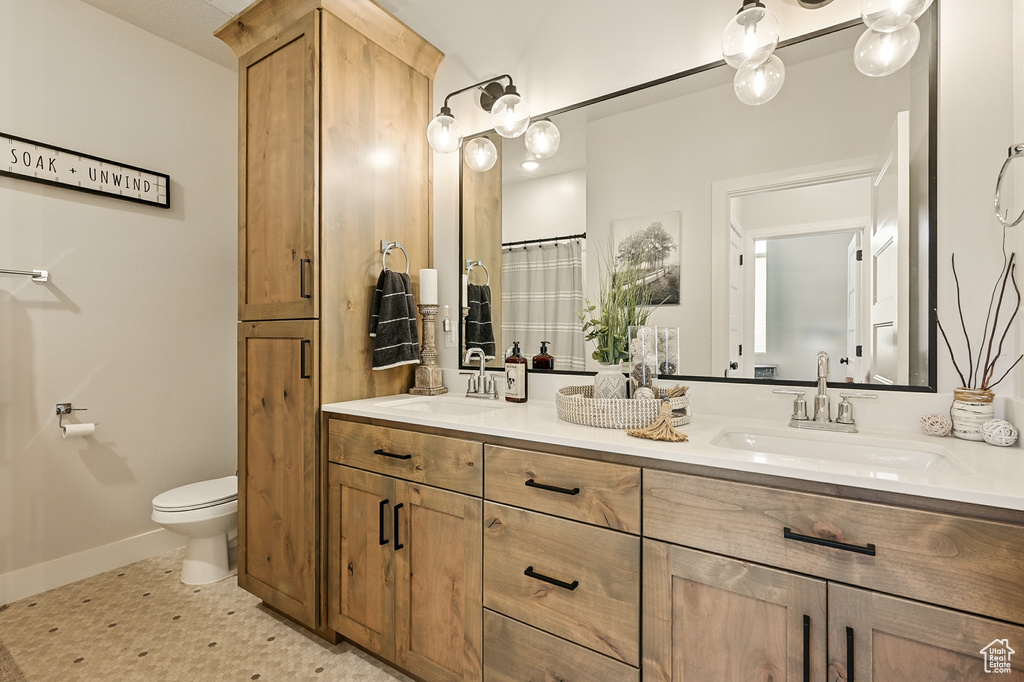 Full bathroom with double vanity, baseboards, and toilet