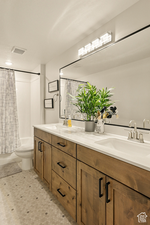 Bathroom featuring double vanity, toilet, and shower / tub combo