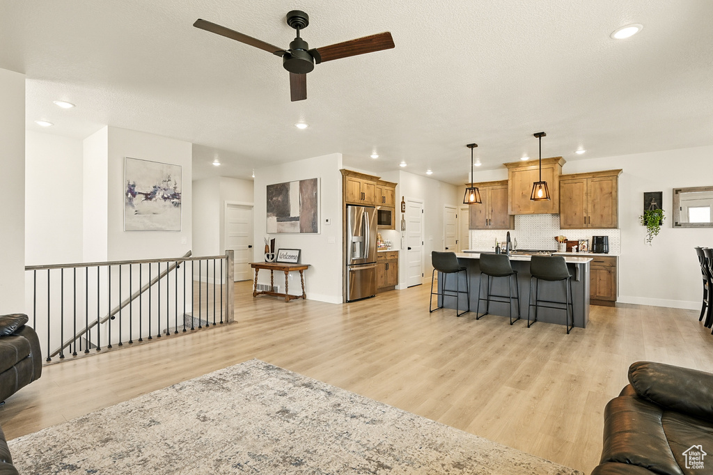 Living area featuring recessed lighting, light wood-type flooring, a ceiling fan, and baseboards
