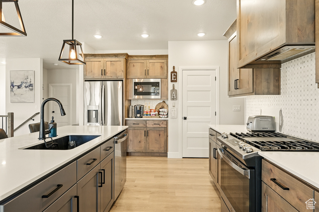 Kitchen featuring stainless steel appliances, a sink, light countertops, light wood-style flooring, and recessed lighting
