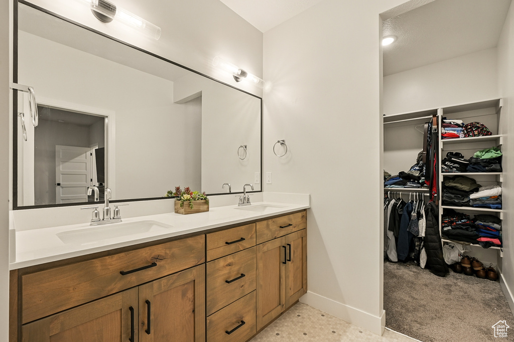 Full bathroom featuring double vanity, baseboards, and a spacious closet