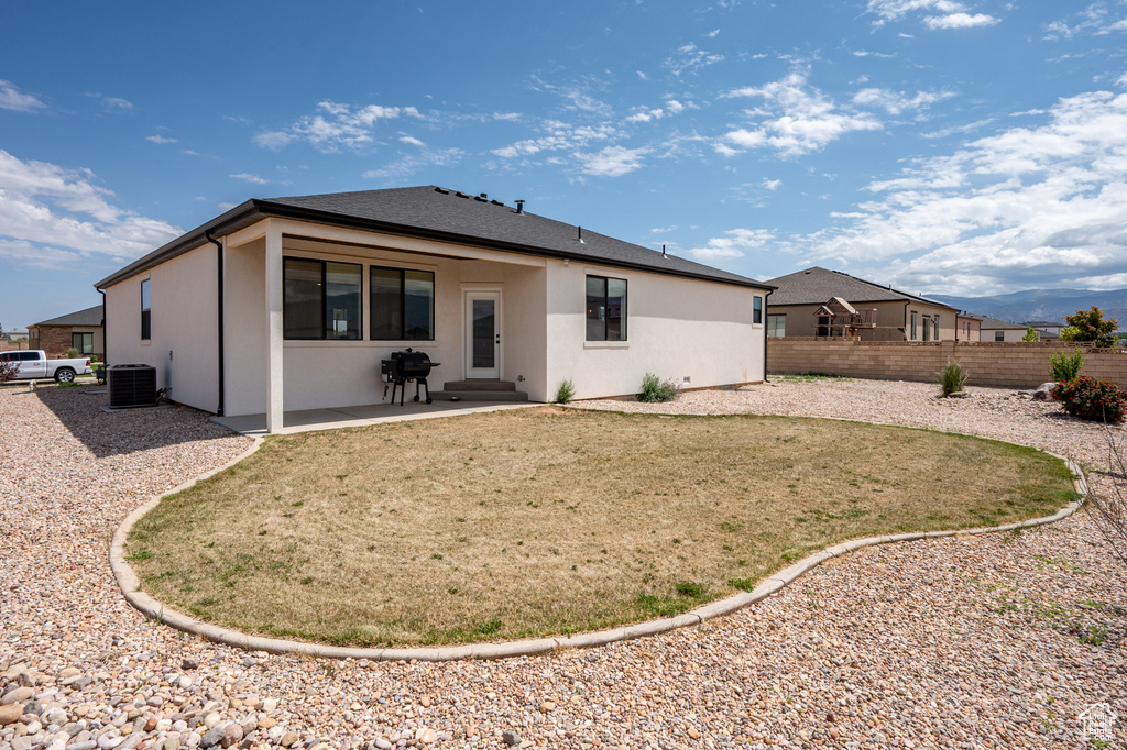 Rear view of house with central AC, stucco siding, and a patio area