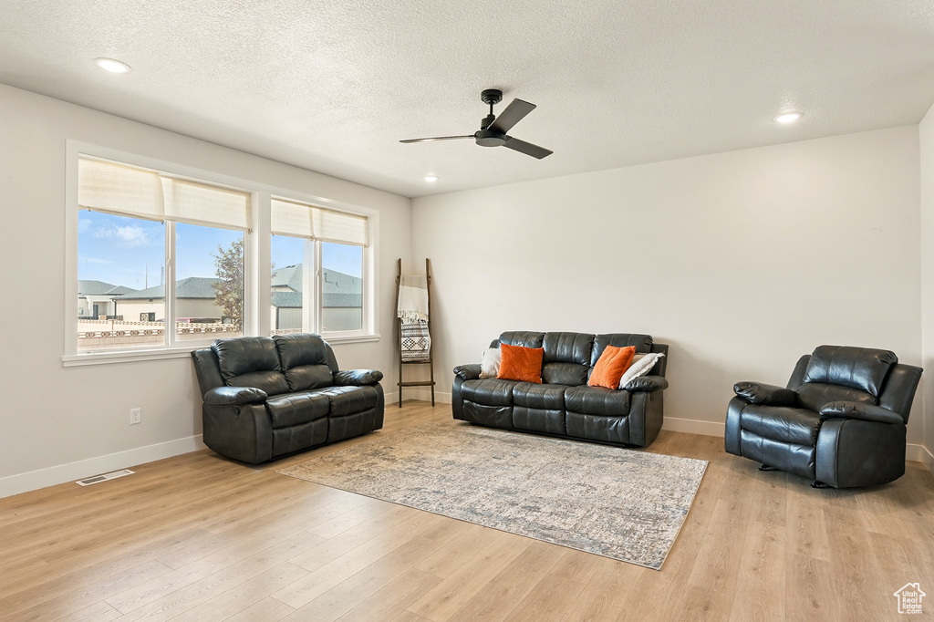 Living room featuring a ceiling fan, wood finished floors, baseboards, recessed lighting, and a textured ceiling