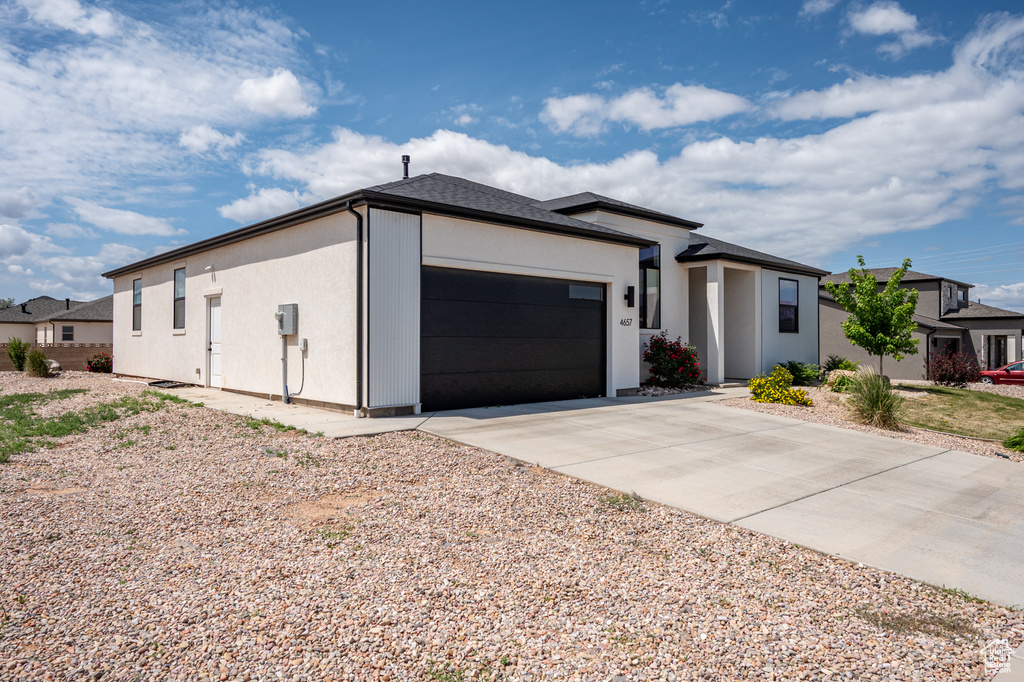 View of front of house with a garage, stucco siding, and driveway