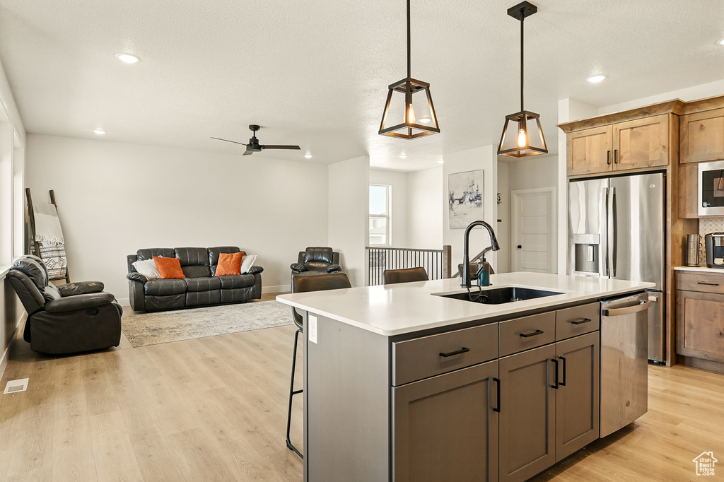 Kitchen with a sink, stainless steel appliances, open floor plan, recessed lighting, and light wood-type flooring