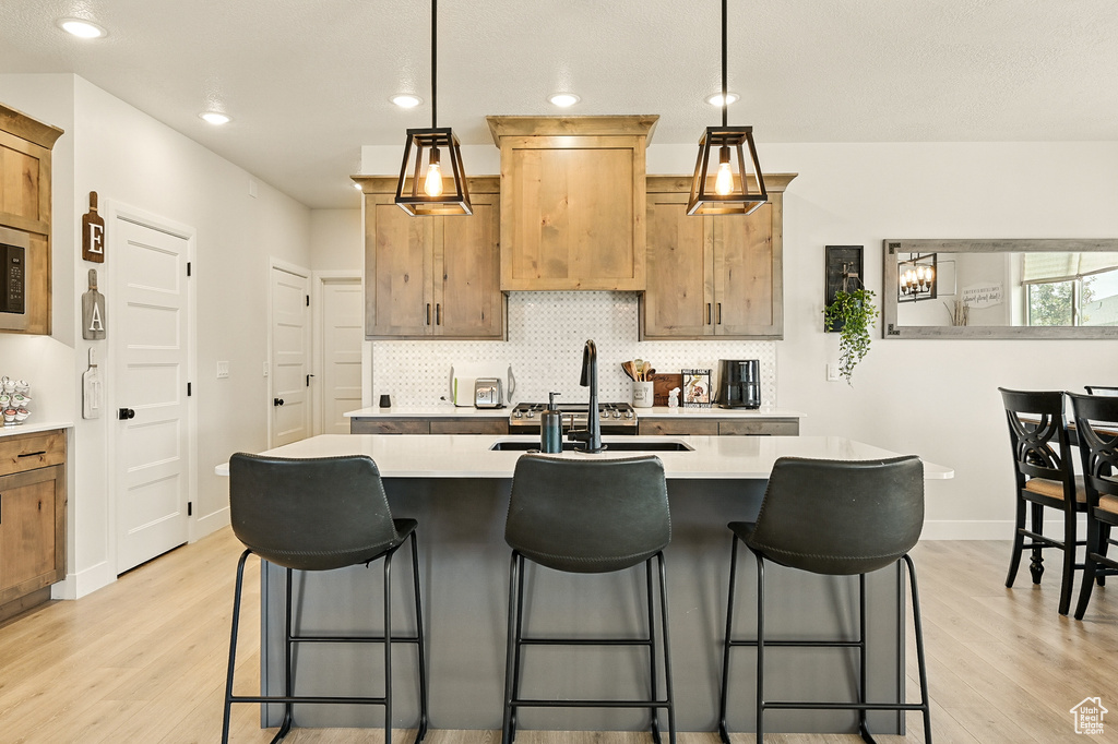 Kitchen with light wood finished floors, light countertops, decorative backsplash, and recessed lighting