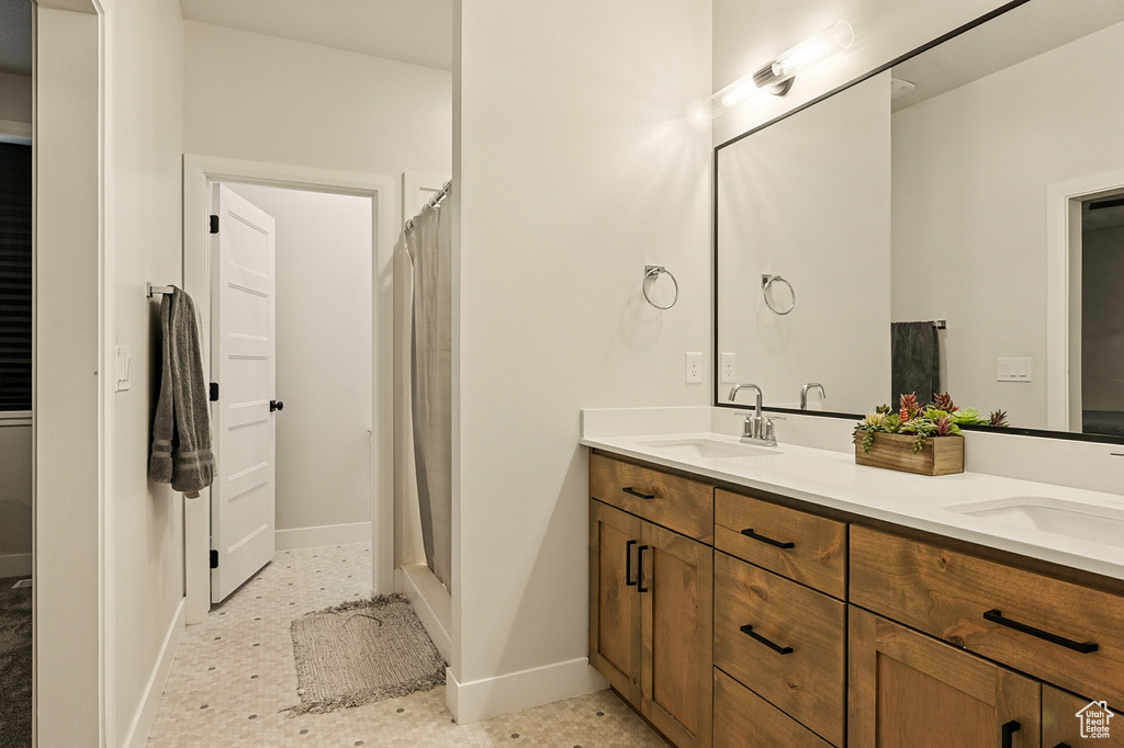 Full bath featuring double vanity, baseboards, and curtained shower