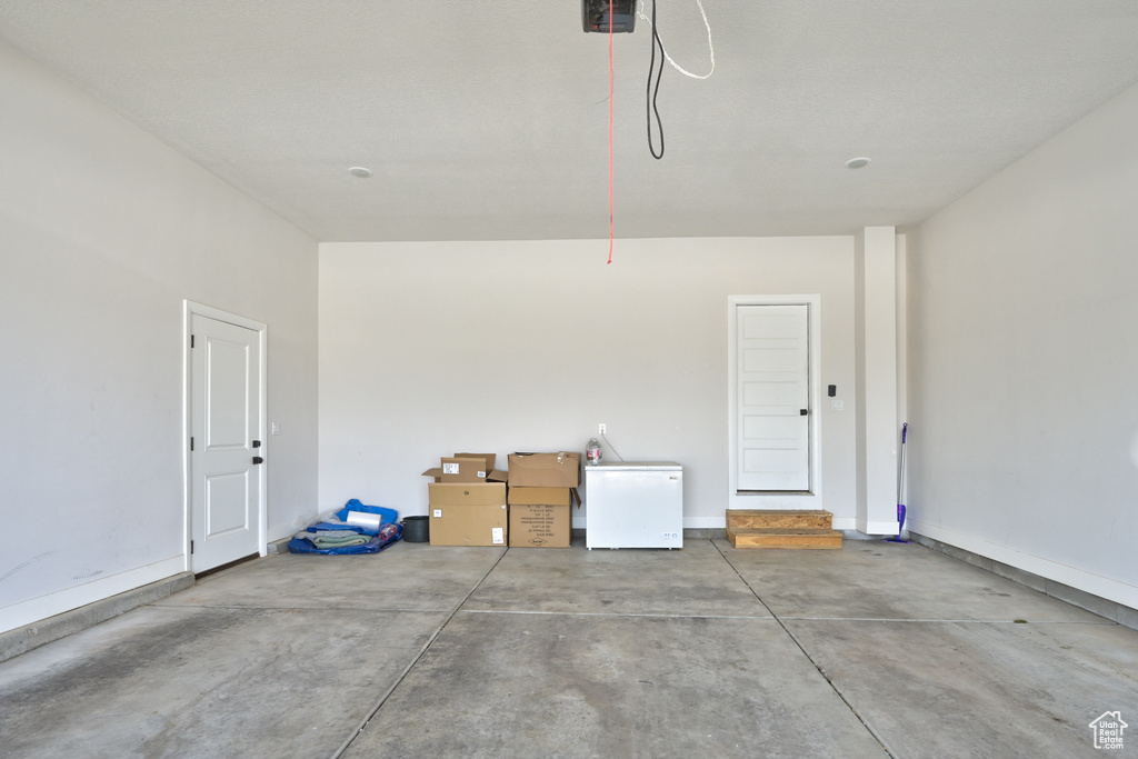 Garage with refrigerator, a garage door opener, and baseboards