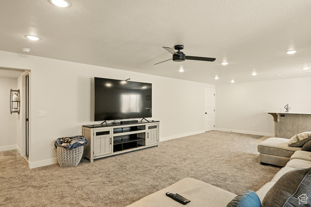 Living room with a ceiling fan, light colored carpet, recessed lighting, baseboards, and a textured ceiling