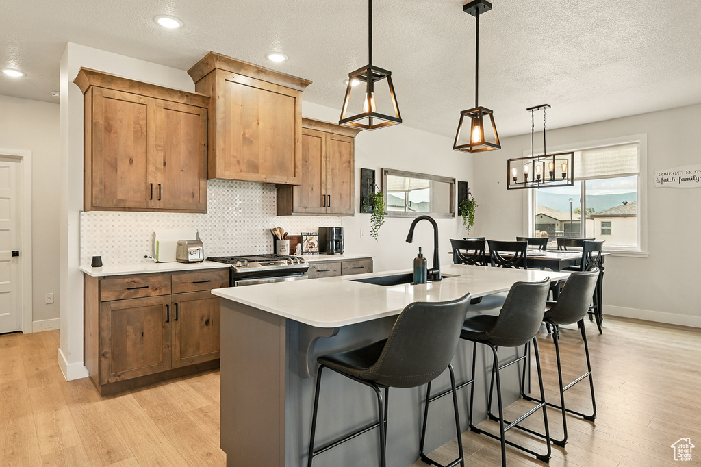 Kitchen with a sink, tasteful backsplash, light countertops, a kitchen bar, and light wood-style flooring