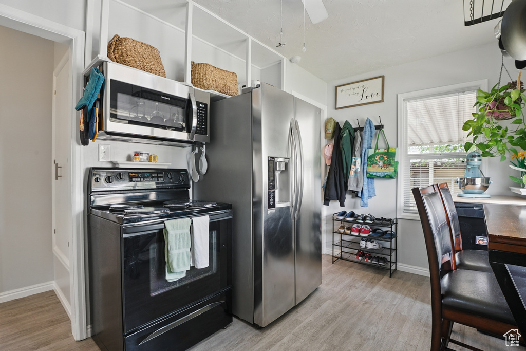 Kitchen featuring stainless steel appliances, wood finished floors, baseboards, and a ceiling fan