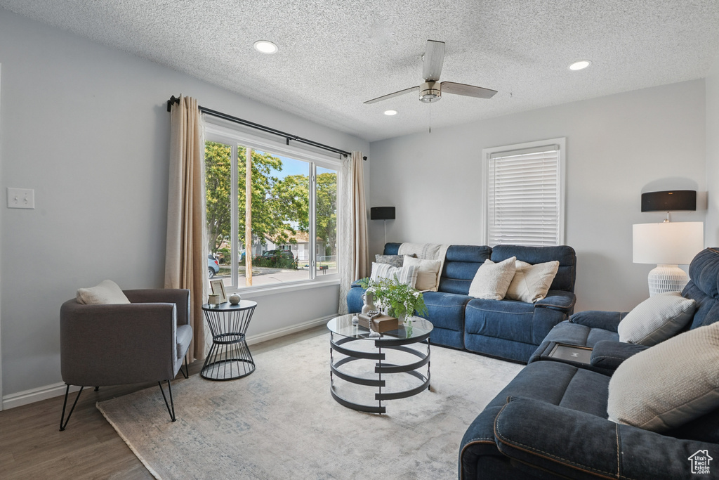 Living area featuring wood finished floors, ceiling fan, baseboards, recessed lighting, and a textured ceiling