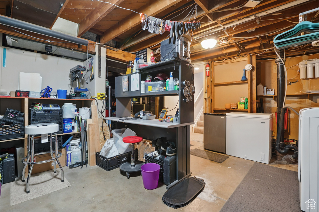 Unfinished basement with white refrigerator, washer and dryer, and fridge