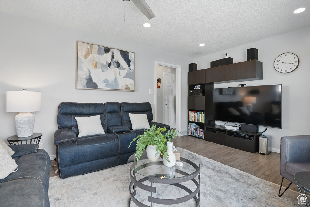 Living room with wood finished floors, ceiling fan, recessed lighting, a textured ceiling, and baseboards