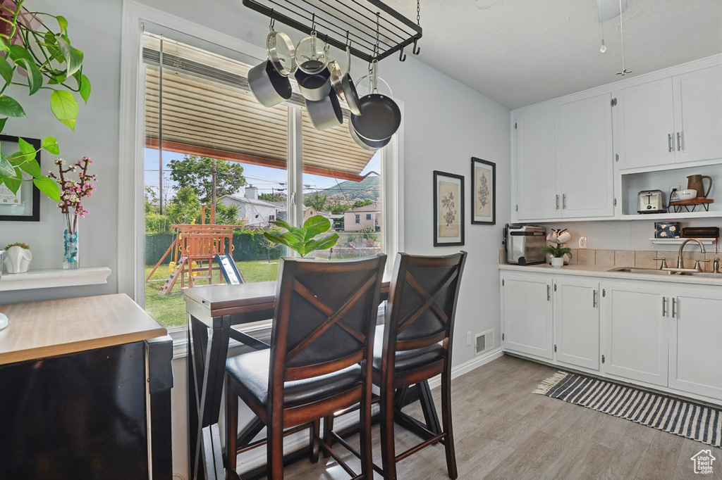 Dining room with light wood-style flooring, a chandelier, and baseboards