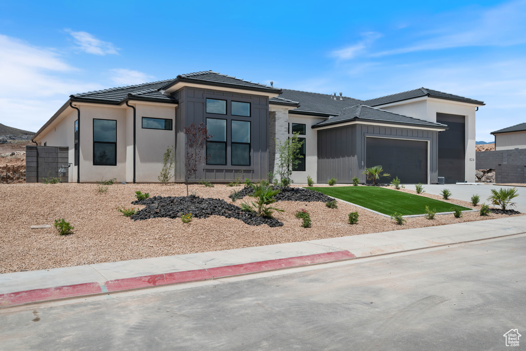 Prairie-style house with a garage, a tile roof, concrete driveway, and stucco siding