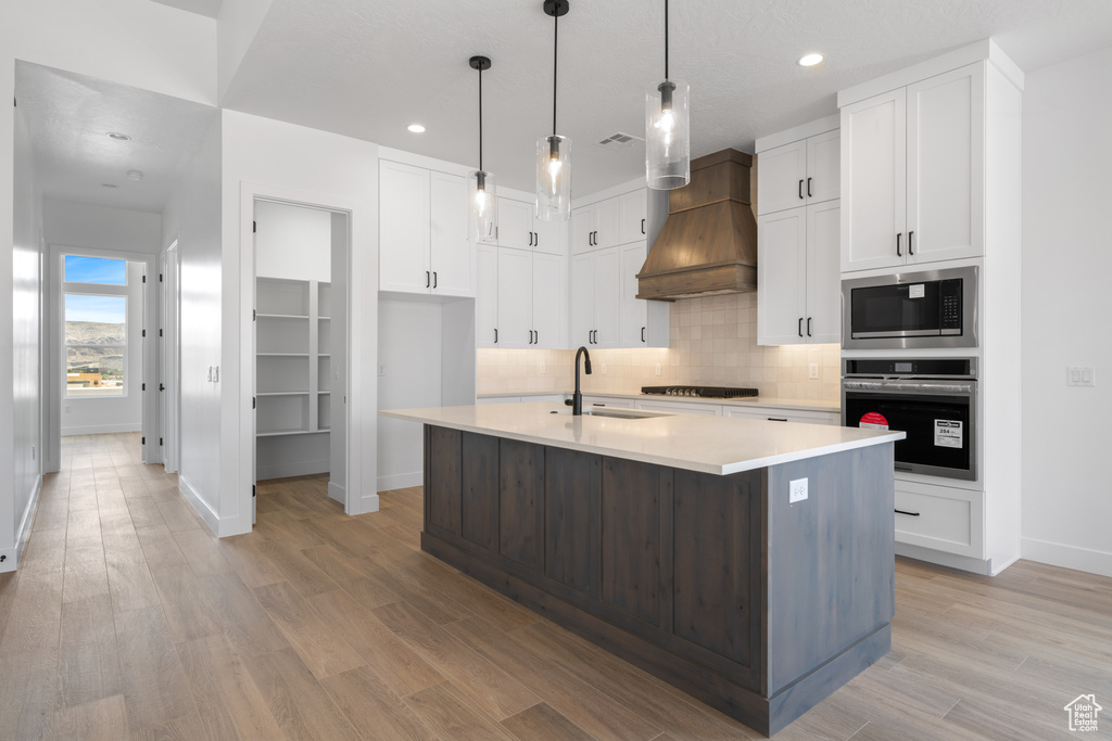 Kitchen featuring appliances with stainless steel finishes, a sink, baseboards, backsplash, and white cabinetry