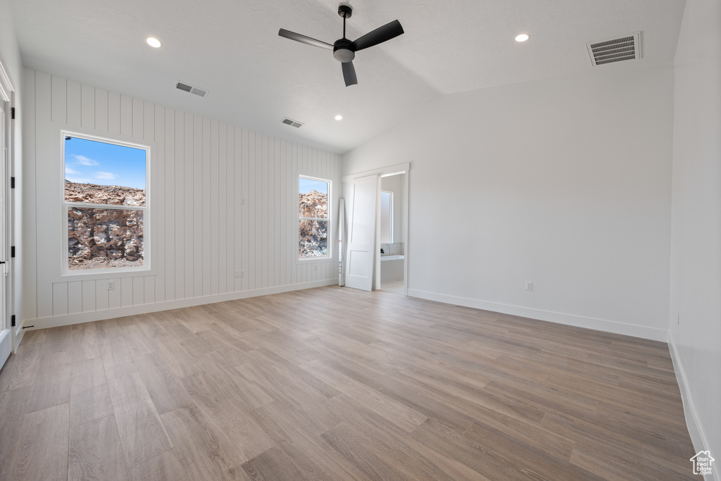 Spare room featuring a ceiling fan, healthy amount of natural light, light wood finished floors, recessed lighting, and vaulted ceiling
