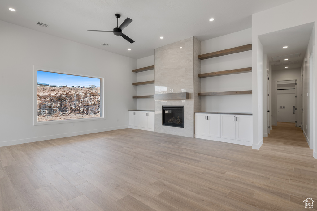 Unfurnished living room with ceiling fan, light wood finished floors, a tiled fireplace, recessed lighting, and baseboards