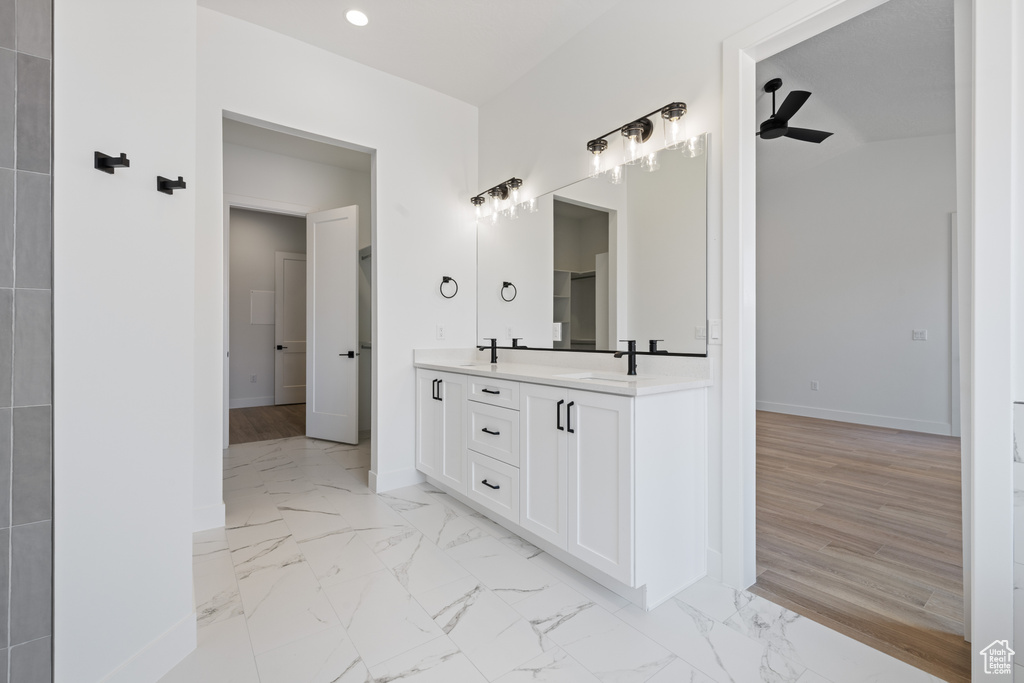 Bathroom with double vanity, baseboards, marble look tiles, and recessed lighting