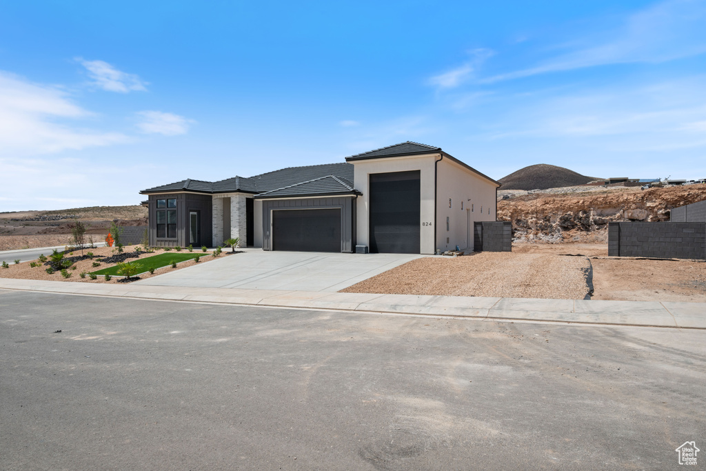 View of front of property with a garage, driveway, stucco siding, and a tile roof