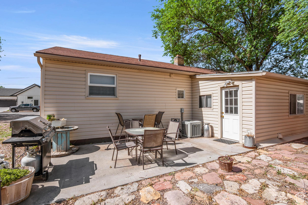 Rear view of house with a chimney, a patio, and cooling unit
