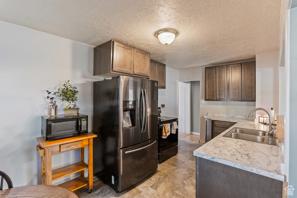 Kitchen with black appliances, a sink, light countertops, and a textured ceiling