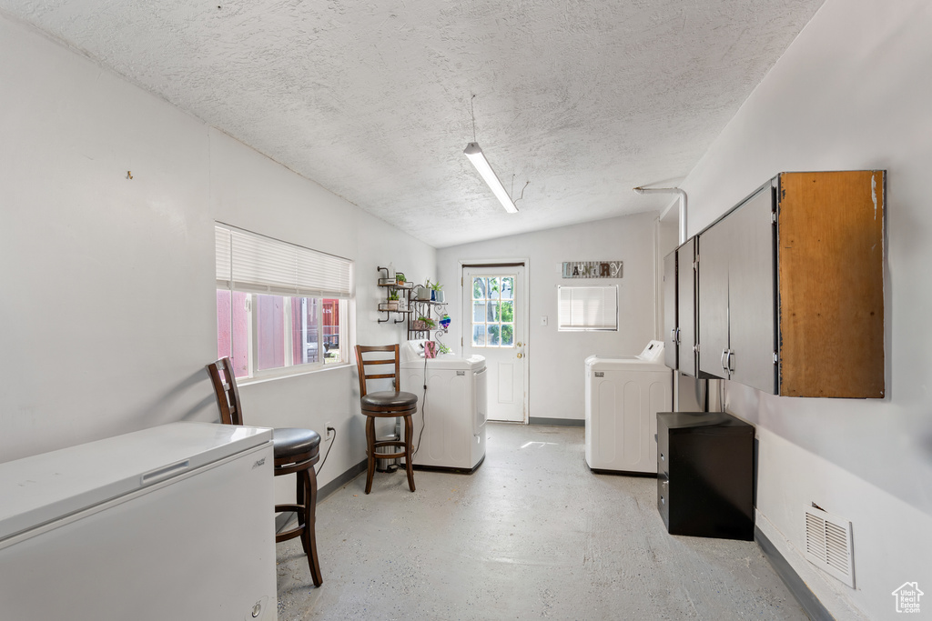 Laundry room featuring a textured ceiling, baseboards, and separate washer and dryer
