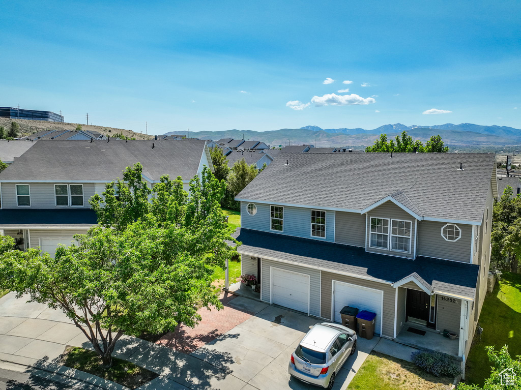 View of front of house featuring concrete driveway, a garage, a mountain view, and roof with shingles