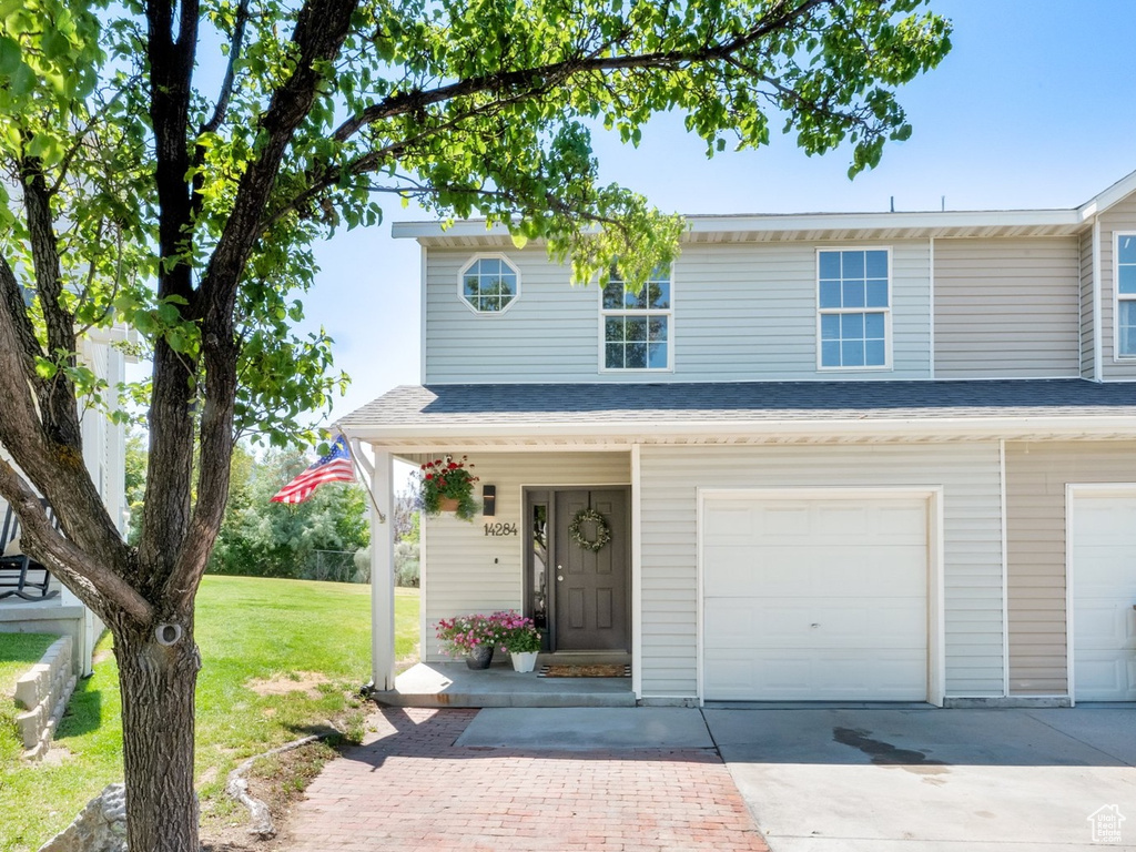View of front of property featuring driveway, a front lawn, and a garage
