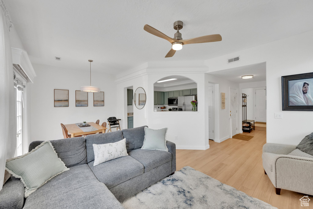 Living area featuring light wood-style flooring, a ceiling fan, and baseboards