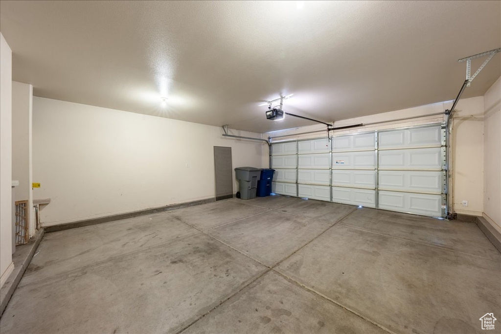Garage featuring a garage door opener and baseboards