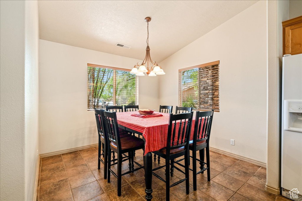 Dining area with a chandelier, vaulted ceiling, and baseboards
